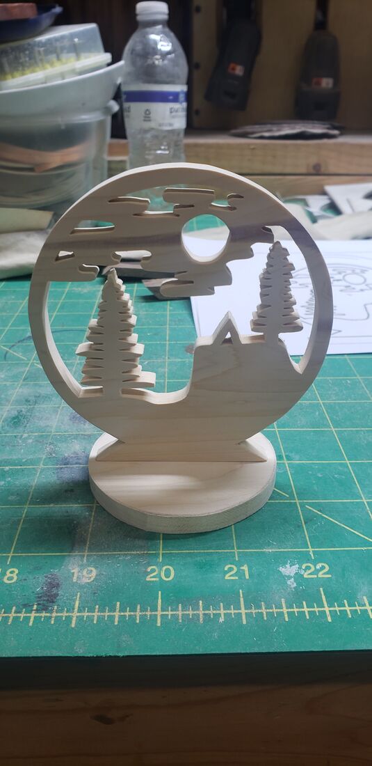 Round stand-up scene with pine trees and a moon