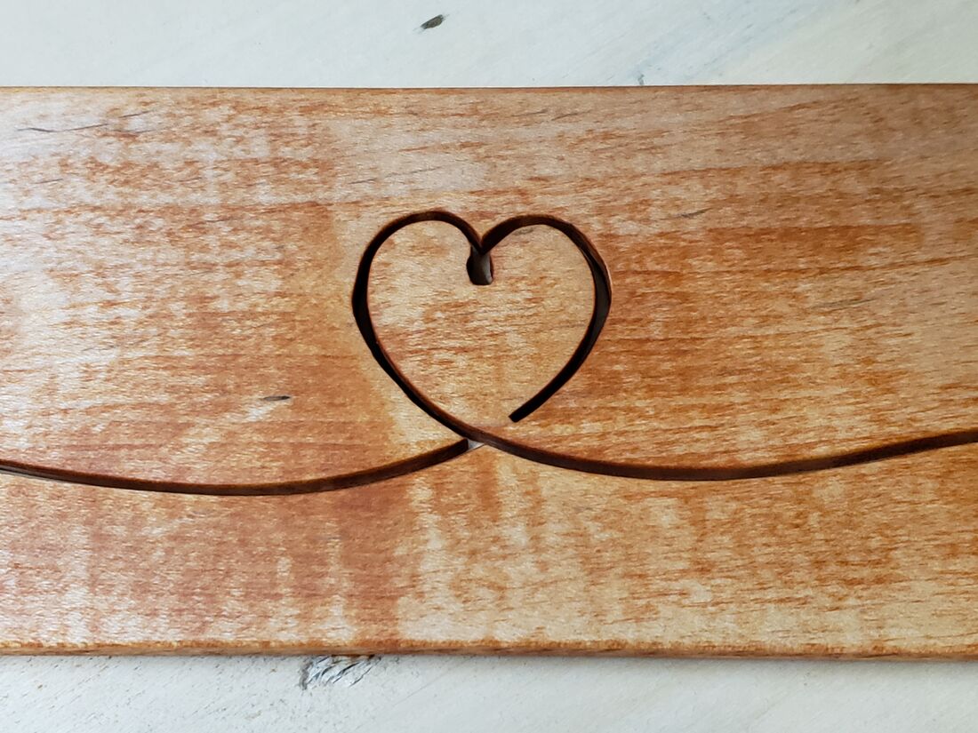 One continuous line forming a heart, cut into an orange-toned board