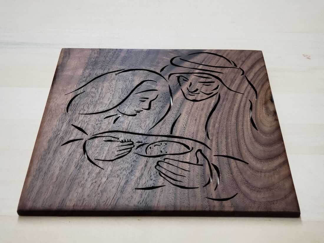 Nativity line art cut into a walnut panel