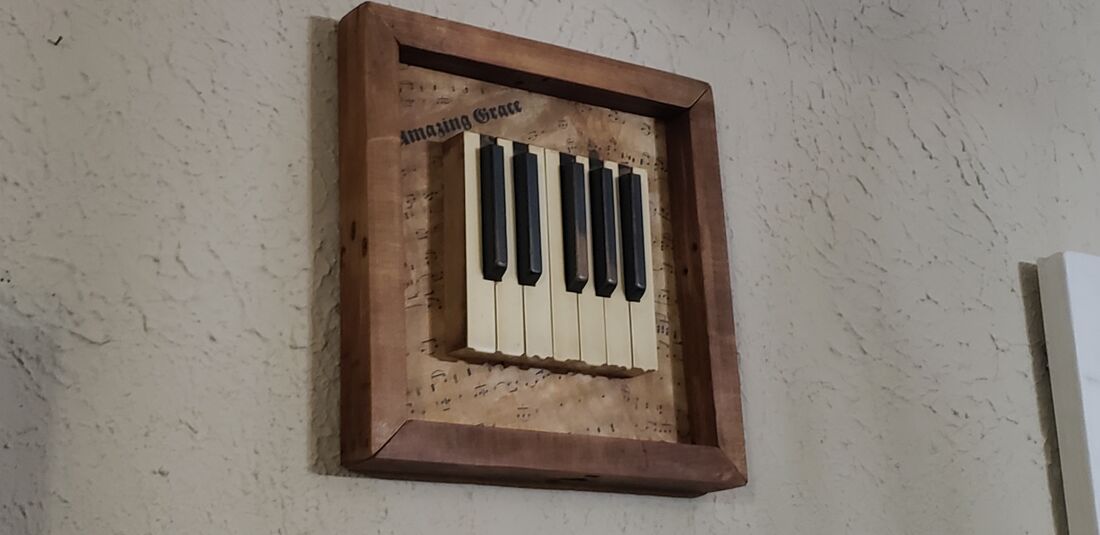 Real piano keys in a wooden shadow box over Amazing Grace sheet music