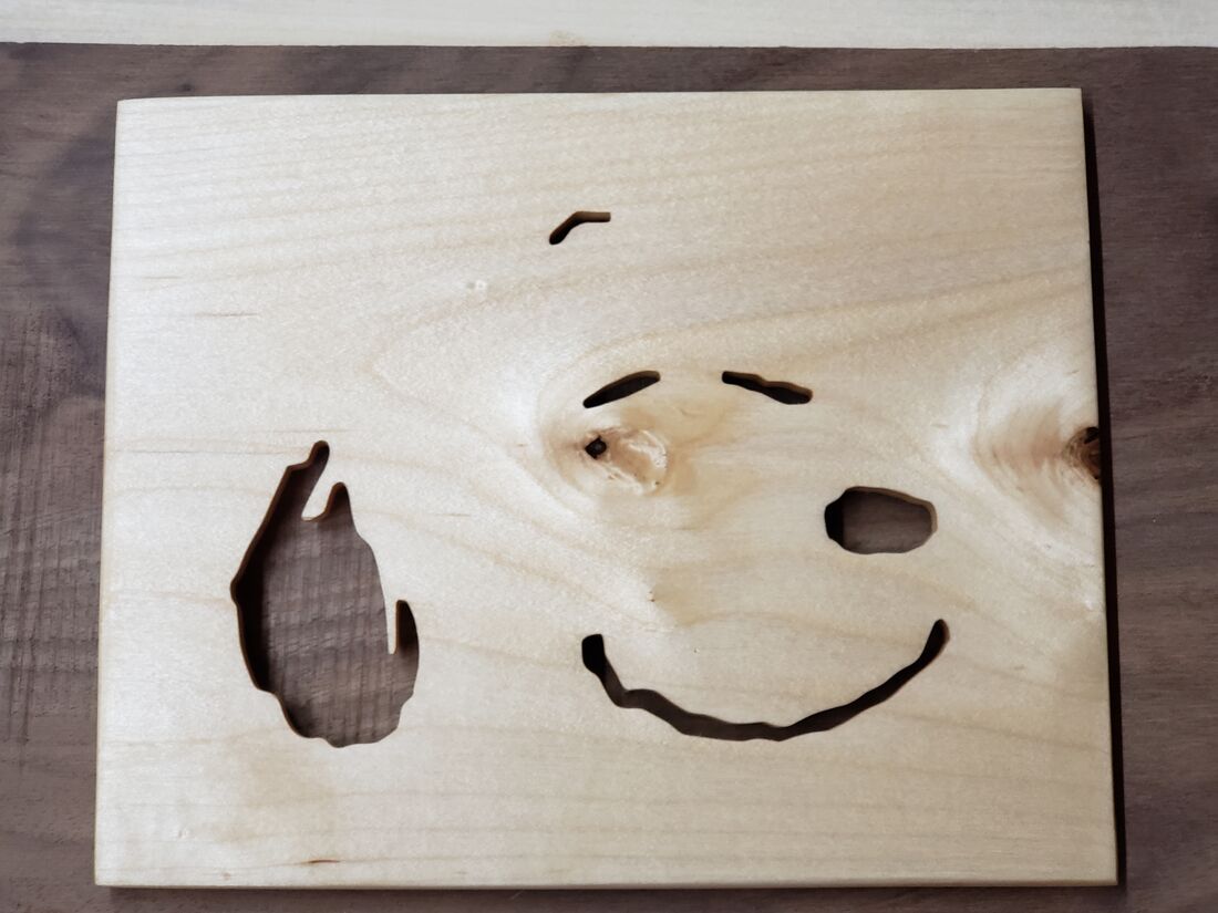 Snoopy face cut into light wood over a dark backer